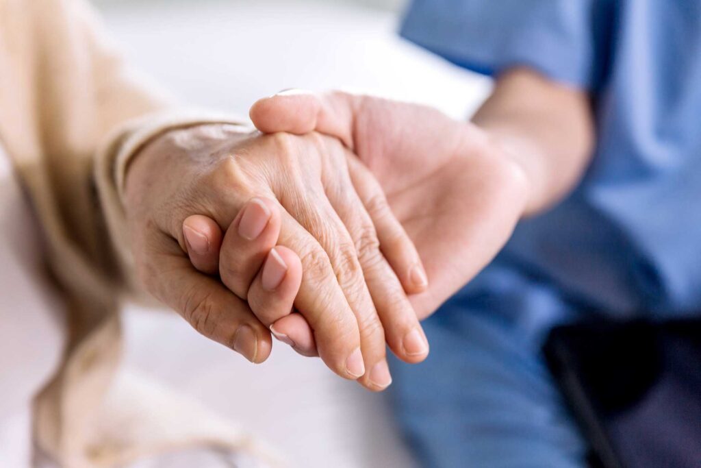 老人の手を握る看護師